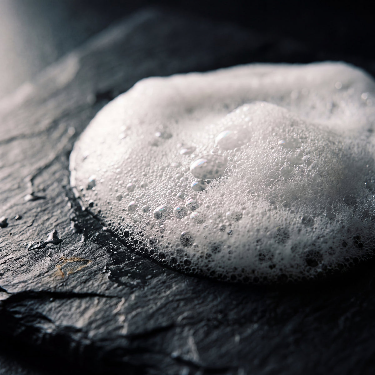 Rich, thick lather of Vellore rosemary thickening shampoo on a stone surface