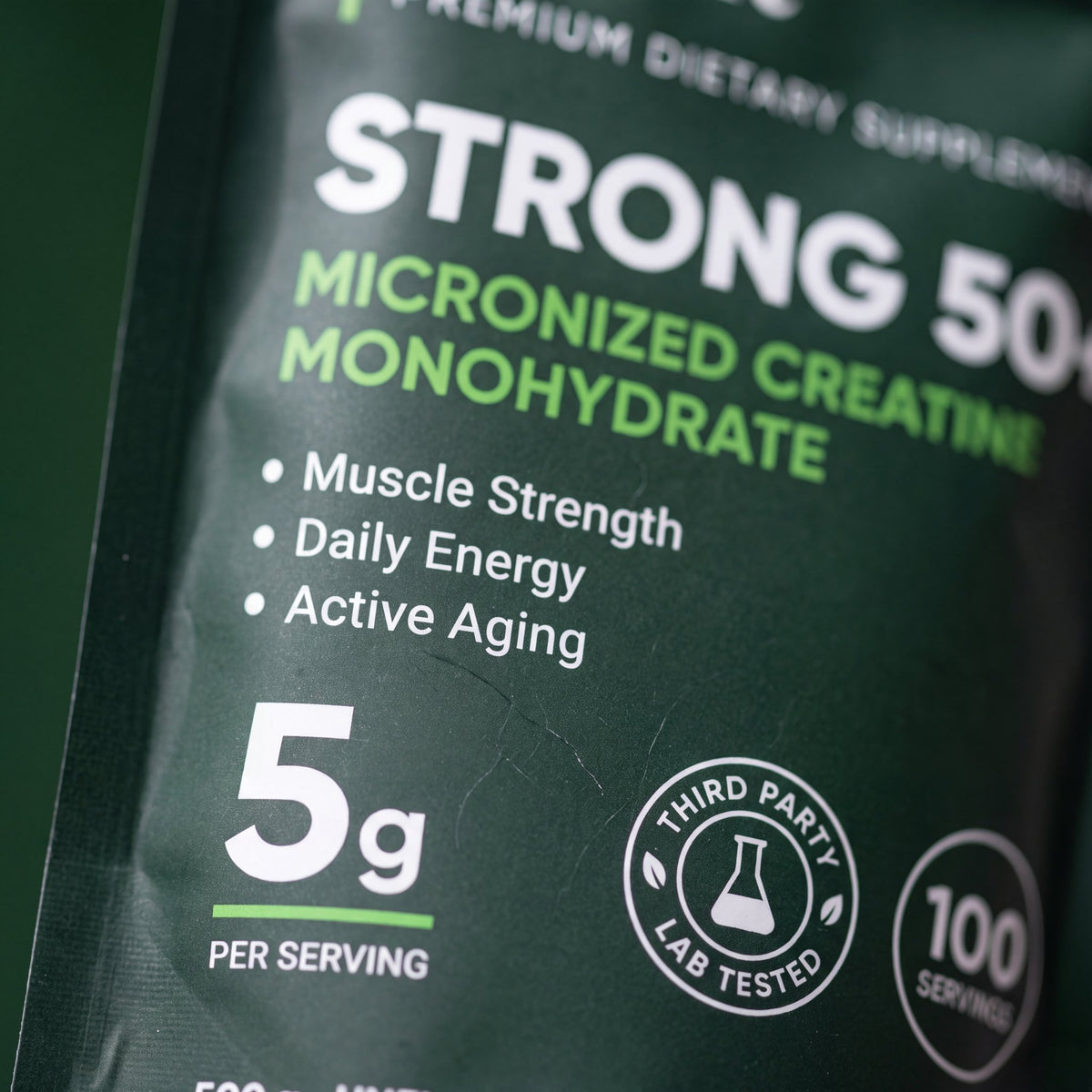 Close-up of the Strong 50+ label: creatine monohydrate 5 g per scoop, unflavoured